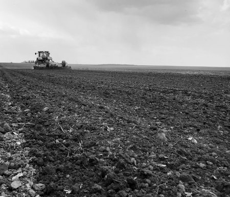 Plowed field by tractor in black soil on open countryside nature, tractor in plowed field, soil to growing tasty vegetables, organic plowed field under the clean dark sky is natural soil for tractorの写真素材