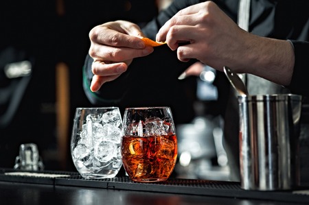 Closeup of bartender hands pouring alcoholic drink into a jigger to prepare a cocktail in a serving glass.の写真素材