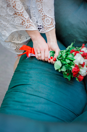 Wedding Bridal bouquet with white and red roses in her hands on blue backgroundの写真素材