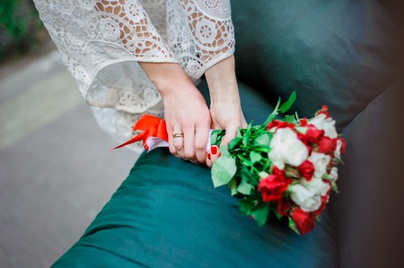Wedding Bridal bouquet with white and red roses in her hands on blue backgroundの写真素材