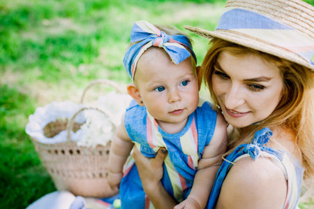 Woman in blue dress raises up her little daughter in the same clothesの写真素材