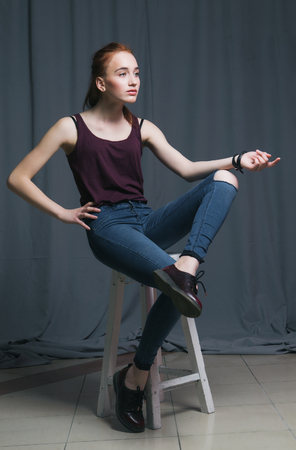 Beautiful woman with long red color straight hair and style makeup. Model posing on grey background.の写真素材