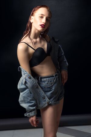 Beautiful woman with long red color straight hair and style makeup. Model posing on dark background.の写真素材