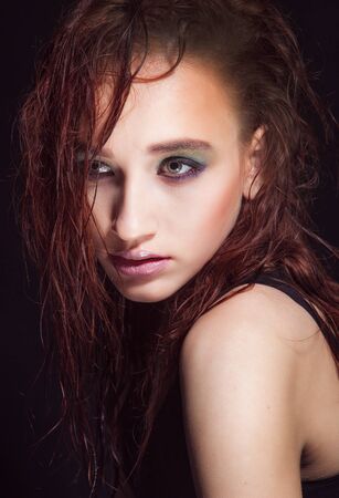 Beautiful woman with long red color straight hair and style makeup. Model posing on dark background.の写真素材