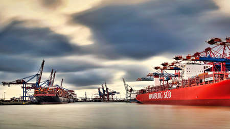 View on the Burchardkai of the Hamburg harbor. Container ship unloaded and loaded during a cloudy day.のeditorial素材