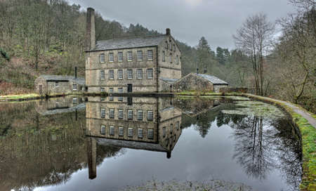gibson mill a water powered mill with main bulding relected in the pond and surroounding trees of hardcastle crags near hebden bridge in west yorkshireのeditorial素材