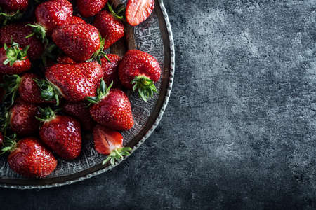 Top view of fresh strawberries in a forged plate on a concrete board.の写真素材