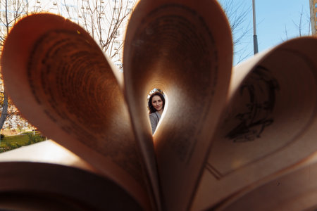a blurred book is twisted into a tube, and in the distance a girl can be seen through the bookの写真素材