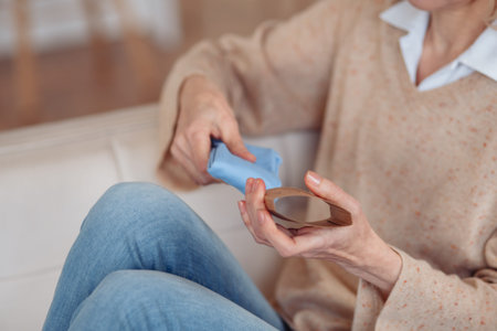 A woman sitting on the floor and putting on white cozy cotton socks on her feet, warming legs and...