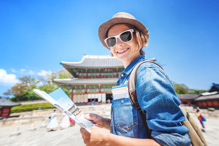 Young woman tourist with map in hand on the background of Asian architecture, travel to Korea, Seoul Asiaの写真素材