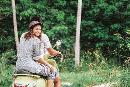 Happy multinational couple traveling on a motorbike in the jungle, honeymoon, vacation,