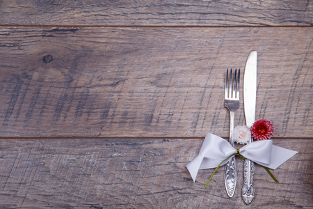 Place table settings with fork and knife, tied with a white satin ribbon, and flowers on an vintage table top view, flat lay, overhead view with space for textの写真素材