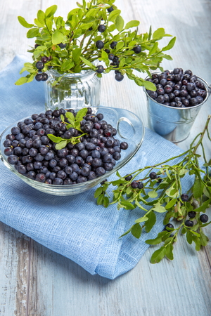 Fresh forest berry, blueberries in a glass plate on a wooden tableの写真素材