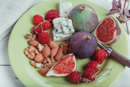 Serving the table, fresh figs, fruits, berries, cheese, nuts on a white wooden backgroundの写真素材