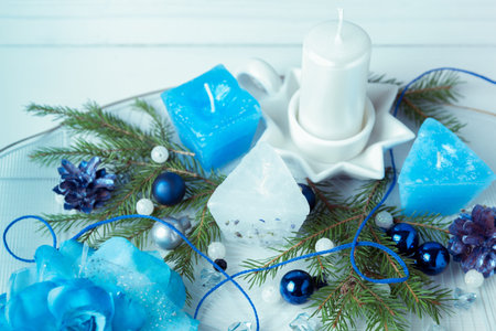 Christmas composition. Pine cones, spruce branches, handmade candles, Christmas blue decor on a wooden white backgroundの写真素材