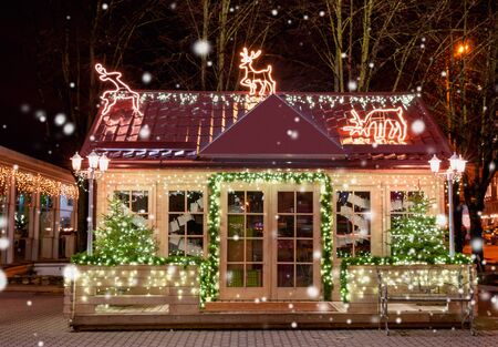 Wooden small house with New Year decoration in the night. Christmas background. Christmas window. Christmas tree outside the window.の写真素材
