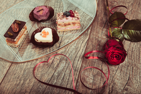 Delicious cupcake for Valentine Day. Red ribbon is lined in the shape of a heart on dark wooden table. Valentines day background, table place setting. Mother's, Women's, Wedding Day concept.の写真素材