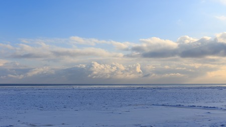 Landscape landscape of the Baltic Sea coast in winter with beautiful clouds and blue sky on a sunny day, water and stones, covered with snow and ice. Kurzeme. Latvia. Europeの写真素材