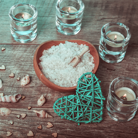 Spa concept in Valentine's Day, candles, handmade heart, seashells, setting for aroma therapy and salt massage on bed, relax and healthy care. Rustic style. Toned image in chocolate, aquamarine tones.の写真素材