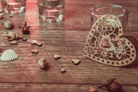 Spa concept in Valentine's Day, candles, handmade heart, seashells, setting for aroma therapy and salt massage on bed, relax and healthy care. Rustic style. Toned image in chocolate, red, pink tones.の写真素材