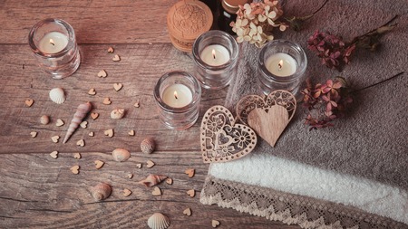 Spa concept in Valentine's Day, candles, handmade heart, dry flowers, seashells, setting for aroma therapy and massage on bed, relax and healthy care. Rustic style. Toned image in chocolate, tones.の写真素材