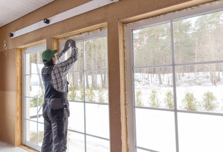 Construction worker thermally insulating eco wooden frame house with wood fiber plates. Latvia