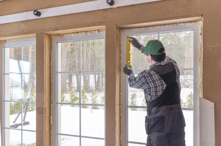 Construction worker thermally insulating eco wooden frame house with wood fiber plates. Latviaの写真素材