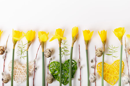 Spring floral border, beautiful fresh daffodils flowers, eggs, hearts isolated on white background....