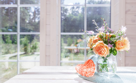 Bouquet of summer roses in glass vase near the windowの写真素材