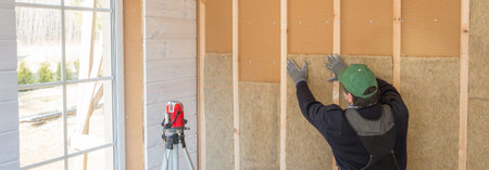 The worker makes finishing works of walls with a white wooden board, using laser line level....