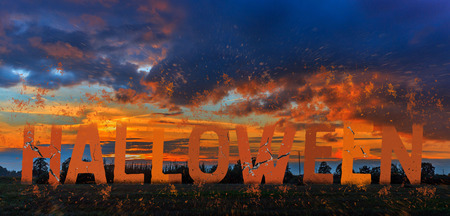 The celebration of the theme of Halloween, the text of Halloween, the huge letters of orange fire hues are falling apart against the mysterious sunset.の写真素材