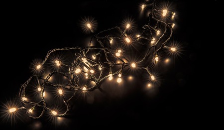 Golden bokeh on a black background. Christmas garlandsの写真素材