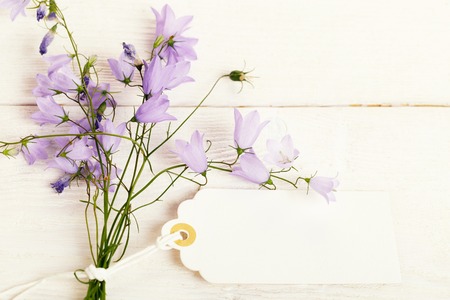 Mothers day card with with a bouquet of delicate wildflowers campanula on white wooden boardの写真素材