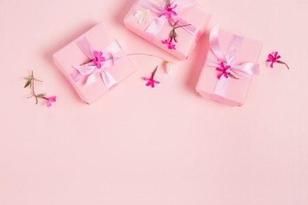 Festive pink background. Gift with satin bow and pink small flowers on light pink pastel background.の写真素材