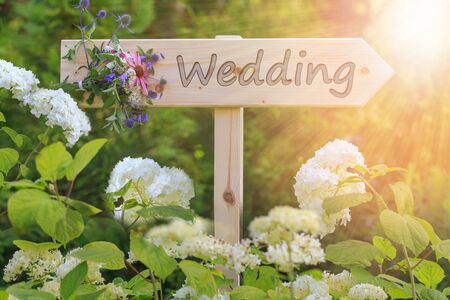 Wedding ceremony wooden sign with a bouquet of wildflowers on a background of white hydrangeasの写真素材