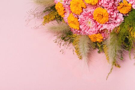 Bouquet of autumn flowers, pink and yellow asters and autumn leaves and herbs on pastel pink backgroundの写真素材
