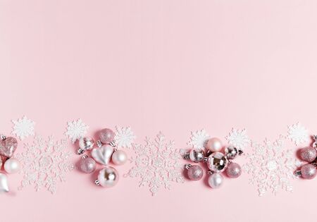Christmas composition. Frame made of balls and snowflakes on pastel pink background.の写真素材