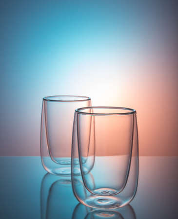 Modern empty glasses with double walls for milk, juice, tea, coffee on a colored backgroundの写真素材
