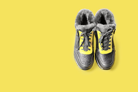 The trendy colors of 2021 are gray and yellow. Fashionable colors of clothes. Sports winter shoes on a yellow background.の写真素材