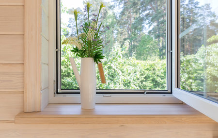 White window with mosquito net in a rustic wooden house overlooking the garden. Bouquet of white...