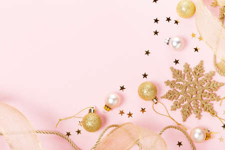 Golden beautiful sparkling christmas decorative toys on pastel pink background.の写真素材