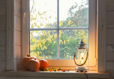 Orange pumpkins on windowsill, candles, autumn leaves, lantern.の写真素材
