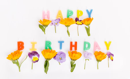 Flat lay composition with flowers and text Happy Birthday on white backgroundの写真素材