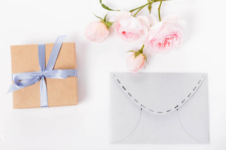 Paper envelope, gift and Valentines pink rose on white background. Flat lay, top view Romantic love letterの写真素材