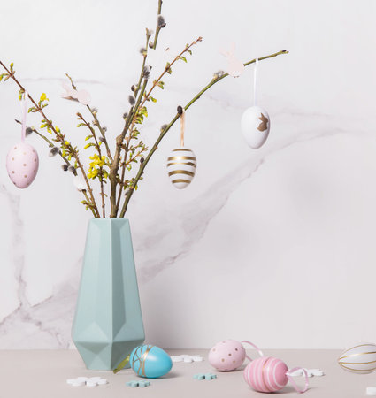 Colorful Easter eggs and spring twigs in vase against the background of marble wallの写真素材