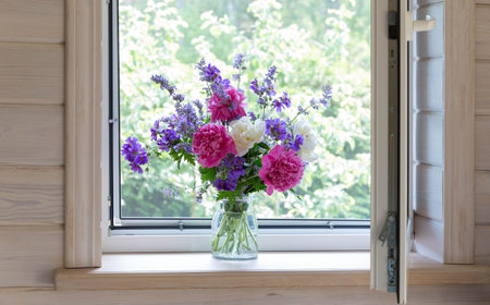 White window with a mosquito net in rustic wooden house. Summer bouquet of peonies on the windowsill.の写真素材