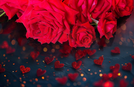 Love and Valentines Day concept chic red roses and bright bokeh hearts on a dark backgroundの写真素材