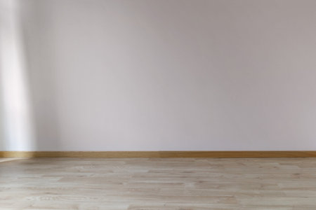 Painted wall in a trendy color with sunlight from the window on the left and wooden floor, empty...