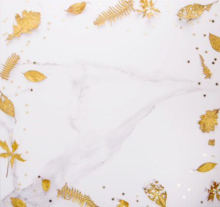 Frame of golden leaves and stars flat lay on marble backgroundの写真素材