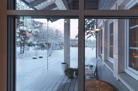 Vinyl windows with winter view of cozy terrace, snow-covered trees and plants, yard